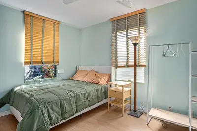 a bedroom with a bed and a table and windows at Steps to Venice Beach Vintage Venice Retreat in Los Angeles