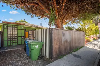 a green trash can sitting next to a fence at Steps to Venice Beach Vintage Venice Retreat in Los Angeles