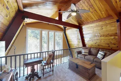 a living room in a log cabin with a ceiling fan at Whistle Stop Cabin in Lake Arrowhead