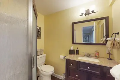 a bathroom with a toilet and a sink and a mirror at Whistle Stop Cabin in Lake Arrowhead