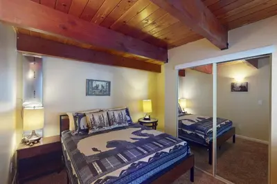 a bedroom with a large bed and a mirror at Whistle Stop Cabin in Lake Arrowhead