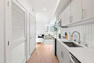 a kitchen with white cabinets and a sink and a table at Bright Studio on Sunset Blvd, Free Parking, Gym, and Pool in Los Angeles