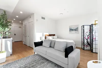 a living room with a couch and a bed at Bright Studio on Sunset Blvd, Free Parking, Gym, and Pool in Los Angeles