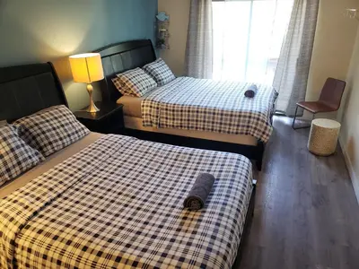 a bedroom with two beds and a lamp and a window at Beverly Hills Studios in Los Angeles