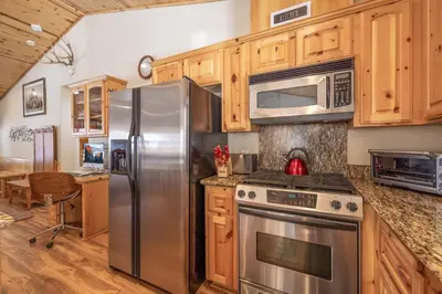a kitchen with stainless steel appliances and wooden cabinets at TimberWood Cabin- 3 Bdr - 2 Bth - Big Game room - Prime Location in Big Bear Lake in Big Bear Lake