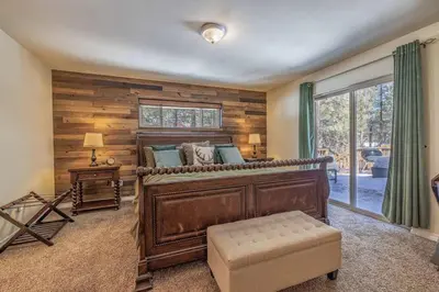 a bedroom with a large bed with a wooden wall at TimberWood Cabin- 3 Bdr - 2 Bth - Big Game room - Prime Location in Big Bear Lake in Big Bear Lake