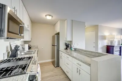 a kitchen with white cabinets and a stove at 2 Mi to Beaches Condo with Patio in Port Hueneme! in Port Hueneme