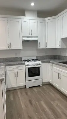 a white kitchen with white cabinets and a stove at Luxury mini house in Hughes-Canoga Park Heliport