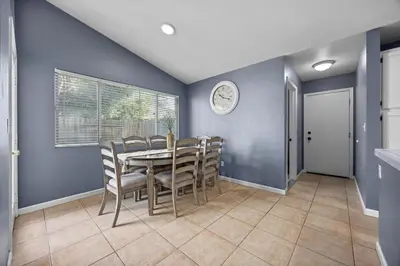 a dining room with a table and chairs and a clock at 3 Bed 2 Bath Newly Furnished - Available Now in Bakersfield