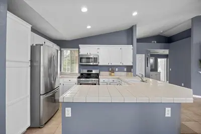 a large kitchen with white cabinets and a refrigerator at 3 Bed 2 Bath Newly Furnished - Available Now in Bakersfield