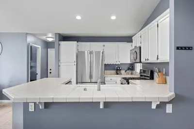 a large kitchen with white cabinets and a refrigerator at 3 Bed 2 Bath Newly Furnished - Available Now in Bakersfield