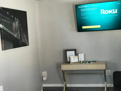 a flat screen tv hanging on a wall with a table at Noah Unit - B in Hawthorne