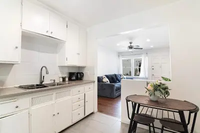 a kitchen with white cabinets and a table with flowers on it at Ground-Floor 1-Bedroom by Beverly Hills Steps from Restaurants, Cafes and Shopping in Los Angeles