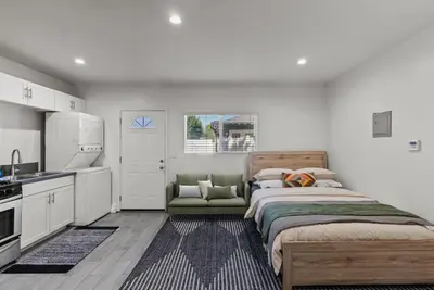 a bedroom with a large bed and a kitchen at Charming Valley Village Studio Retreat in Los Angeles