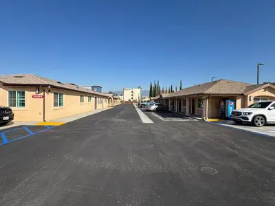 an empty parking lot with cars parked in front of buildings at Dutch Motel in Loma Linda
