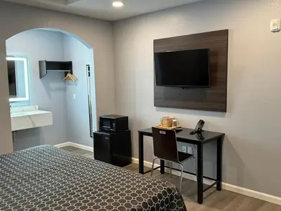 a bedroom with a bed and a desk with a television at Dutch Motel in Loma Linda
