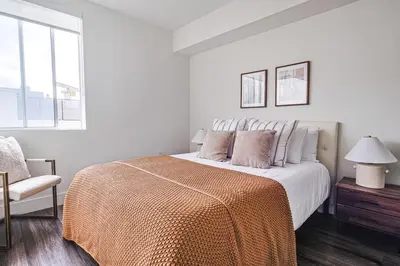 a white bedroom with a bed with an orange blanket at Modern 2BD - 5 min to Santa Monica Pier! in Los Angeles