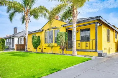 a yellow house with palm trees in front of it at 8 Mi to Dtwn LA Apt with Shared Patio! in Los Angeles