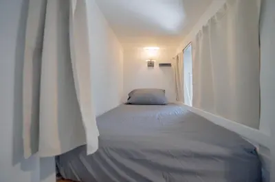 a bed in a white room with a window at Burlington Hostel in Los Angeles