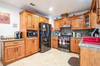 a kitchen with wooden cabinets and a black refrigerator at Peaceful Oasis in Anaheim