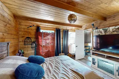 a bedroom with wooden walls and a bed with blue cushions at Relaxing Retreat with Deck, 1 Mi to Lake Arrowhead! in Cedar Glen