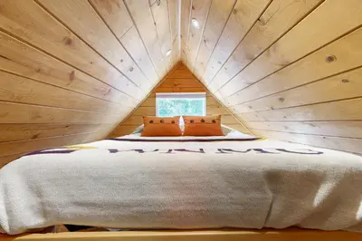 a bed in a tree house with a window at Relaxing Retreat with Deck, 1 Mi to Lake Arrowhead! in Cedar Glen