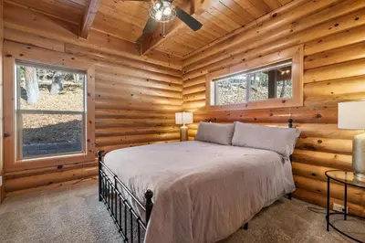 a bedroom with a bed in a log cabin at Bear Creek Haven -Nestled between the Village & Lake! in Big Bear Lake