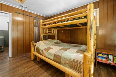 a bedroom with two bunk beds and wooden walls at Mountain Xscape - Hot Tub, Fireplace, Deck, Barbeque in Big Bear Lake