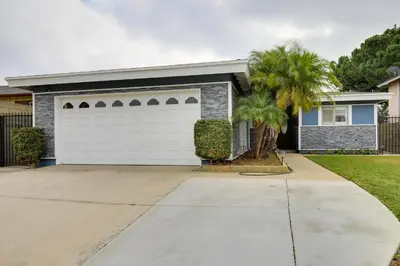 a house with a white garage door and palm trees at 10 Mi to Redondo Beach Carson Home with Pool Table! in Carson