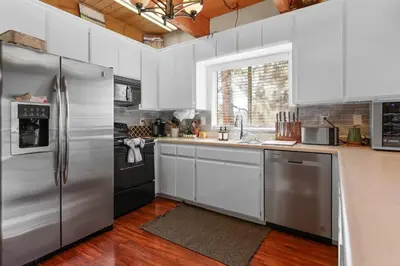 a kitchen with stainless steel appliances and white cabinets at The Cedar Bear Lodge, Jacuzzi with an Outdoor Patio & BBQ in Big Bear City Airport