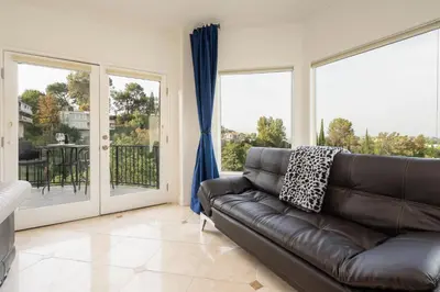 a living room with a leather couch and large windows at Luxury Modern w/ Great LA Views in Woodland Hills