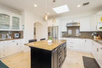 a large kitchen with white cabinets and a black island at Luxury Modern w/ Great LA Views in Woodland Hills
