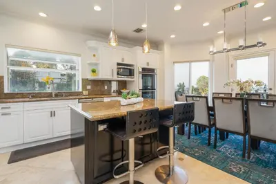a kitchen with white cabinets and a large island with bar chairs at Luxury Modern w/ Great LA Views in Woodland Hills