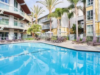 a swimming pool in front of a building with palm trees at A Symphony of Blue - Panoramic Ocean Frontage - 3BR Marina Suite in Los Angeles
