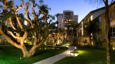 a park with a tree and a bench next to a building at A Symphony of Blue - Panoramic Ocean Frontage - 3BR Marina Suite in Los Angeles