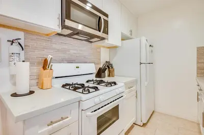 a white kitchen with a stove and a refrigerator at 1 Mi to Dtwn Melrose Cozy Condo with Patio in Los Angeles