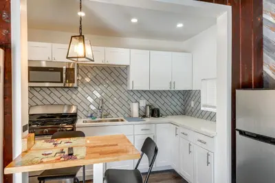 a kitchen with white cabinets and a wooden table at Private Deck and Views Frazier Mountain Cabin in Frazier Park