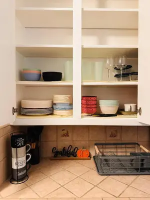 a kitchen cabinet filled with plates and bowls at Los Angeles Cherry Blossom in Monterey Park