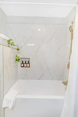 a bathroom with a white tub and marble walls at Remodeled House Near Disneyland in Fullerton