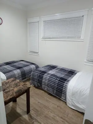 a bedroom with two beds and a table and windows at Vacation Unit is Available for Business and Family Trip in Long Beach