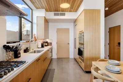 a kitchen with wooden cabinets and a large window at The Santa Monica Sunset - 5k sq ft beachfront luxury in Los Angeles