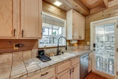 a kitchen with wooden cabinets and a sink and a window at Walkable Green Gables Cottage in Lake Arrowhead in Lake Arrowhead