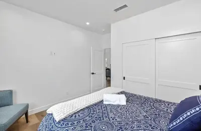 a white bedroom with a bed and a chair at Coastal Modern 3 Bed 2 Bath, Pet Friendly in Hawthorne