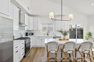 a kitchen with white cabinets and a table with chairs at Coastal Modern 3 Bed 2 Bath, Pet Friendly in Hawthorne