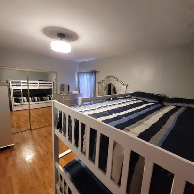 a bedroom with a white bed with a striped comforter at 3 bedroom 2 bath home with Jacuzzi near Beverly Hills, wi-fi, Jacuzzi, Roku, BBQ, giant games family fun in Los Angeles