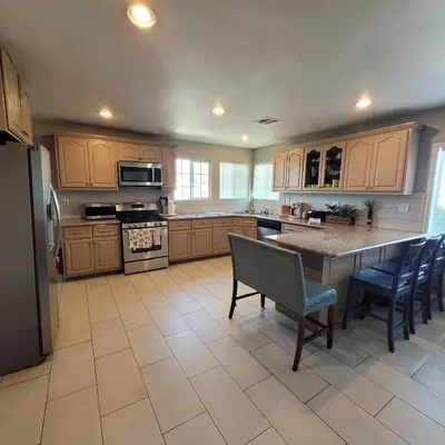 a large kitchen with wooden cabinets and a table and chairs at 3 bedroom 2 bath home with Jacuzzi near Beverly Hills, wi-fi, Jacuzzi, Roku, BBQ, giant games family fun in Los Angeles