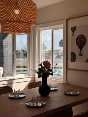 a dining room table with plates and a vase with flowers at Cozy private room B in S Central LA in Los Angeles