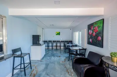 a living room with chairs and tables and a kitchen at Hotel Avenida Victorville I 15 in Victorville