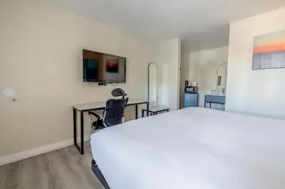 a bedroom with a large white bed and a desk at Hotel Avenida Victorville I 15 in Victorville