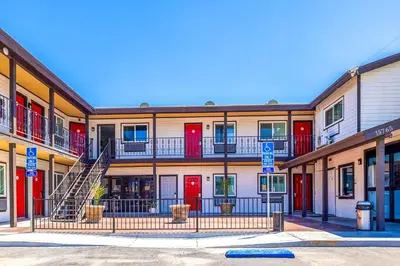 an apartment building with red doors and a staircase at Hotel Avenida Victorville I 15 in Victorville